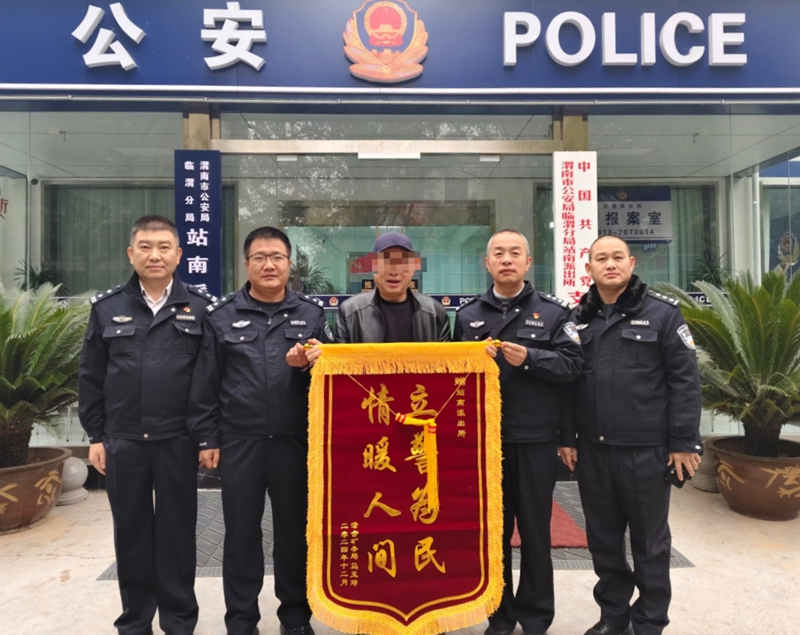 馬先生將一面錦旗送到臨渭公安分局站南派出所民警手中，為民警暖心幫助其找回“丟失”車輛點(diǎn)贊。